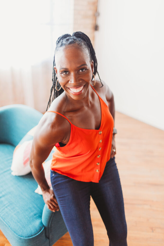 Candace smiles in business attire that shows off her well-toned arms and traps.